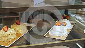 Bakery vitrine with cakes and pastries on glass shelves.