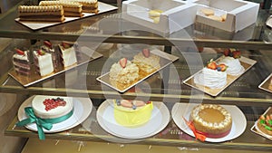 Bakery vitrine with cakes and pastries on glass shelves.