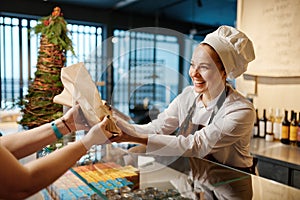 Bakery worker selling fresh tasty pastry and bread in bakery shop