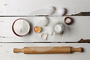 Baking background. Cooking ingredients for yeast dough and pastry, eggs, flour and milk on white rustic wood. Top view