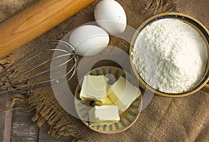 Baking background, dough recipe ingredients butter, eggs, flour, on wooden table.