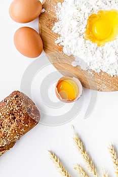 Baking background with eggs, flour and bread on white desk. Top view.