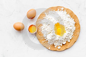 Baking background with eggs and flour on white desk. Top view.