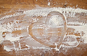 Baking background with heart shape and flour on a dark table. Copy space for text