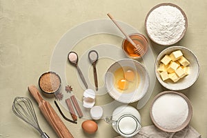 Baking background. Baking ingredients are flour, butter, milk, spices, eggs, sugar and honey. Concrete beige background. Top view