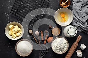 Baking background. Baking ingredients: flour, eggs, sugar, butter, milk and spices on black stone background. Top view