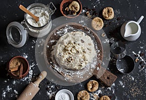 Baking background. Ingredients for preparation of the cookies with dried figs and raisins. On a dark background, top view.