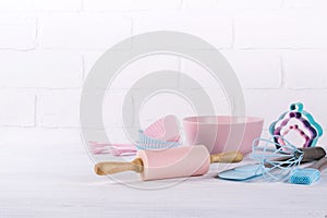 Baking background with kitchen tools: rolling pin, wooden spoons, whisk, sieve, bakeware and shape cookie cutter on white