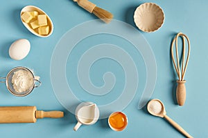Baking background with whisk, egg, flour , sugar, butter on blue table top view. Flat lay