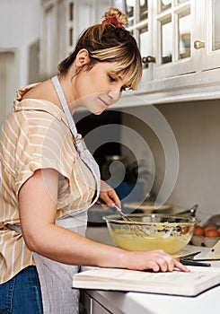Baking, book and recipe with woman in kitchen of home for guide, instructions or reading steps. Cooking, food and small