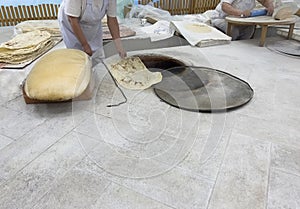 Baking the bread in tandoor. Woman rolls out dough. Making traditional flat cakes. Making bread in traditional bakery shop