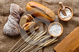 Baking bread with wheat flour and ears on table rystic background top view