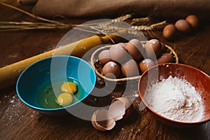 Baking cake in rural kitchen - dough recipe ingredients eggs, flour, sugar on vintage wooden table from above.