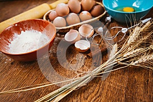 Baking cake in rural kitchen - dough recipe ingredients eggs, flour, sugar on vintage wooden table from above.