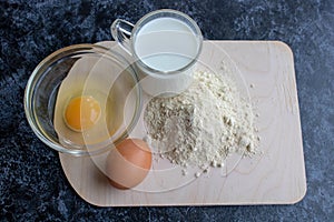 Baking a cake in a village kitchen - recipe dough Ingredients eggs, flour, milk, on a dark wooden table on top