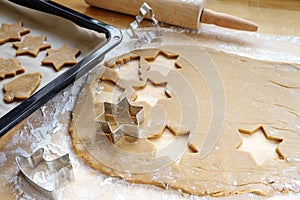 Baking Christmas gingerbread, rolled out dough with cookie cutters, baking tray and rolling pin on a wooden kitchen worktop, copy