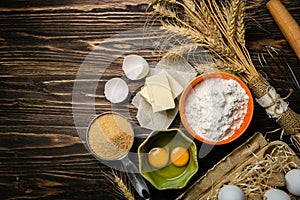 Baking concept - baking ingredients butter, flour, sugar, eggs on rustic wood background