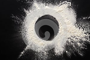 Baking concept on black background, sprinkled flour circle with copy space