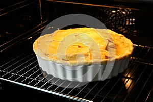 Baking dish with raw homemade apple pie in oven, closeup