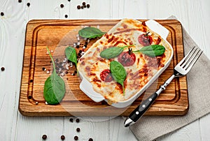 Baking dish with tasty vegetable lasagna on wooden background