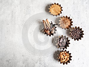 Baking ingredients: brown sugar, cocoa, almond, dark chocolate and spices on gray marble background. Top view