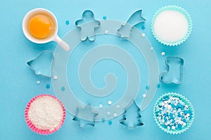 Baking ingredients and cookie cutter on blue background, flat lay