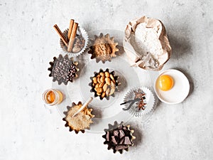 Baking ingredients: flour, brown sugar, egg, cocoa, almond, dark chocolate and spices on grey background