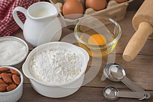 Baking ingredients flour, egg, milk, almonds, sugar on wood table