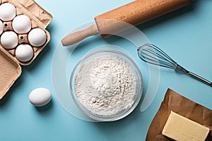 Baking ingredients flour, eggs, butter with rolling pin on a bright background