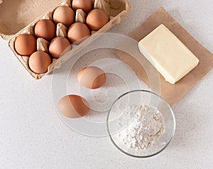 Baking ingredients: flour, eggs, butter on the table.