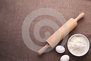 Baking ingredients. Flour, eggs, wheat and rolling pin on table cloth.