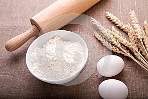 Baking ingredients. Flour, eggs, wheat and rolling pin on table cloth.