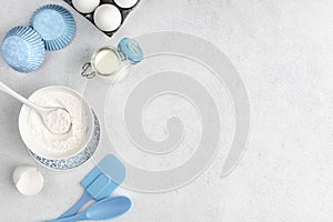 Baking ingredients: flour, eggs, yolk, on a white table.