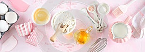 Baking ingredients and kitchen utensils on a pink background, top view.