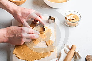 Baking ingredients and kitchen utensils on a white background top view. Female or man hands preparing heart sugar cookies. Baking
