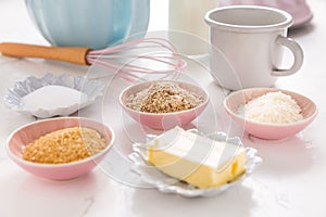 Baking ingredients and kitchen utensils on white wooden background