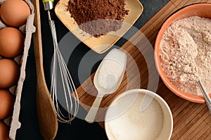 Baking ingredients on a stone table: eggs, flour, sugar and cacao
