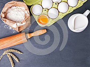 Baking ingredients and tools on the black stone background