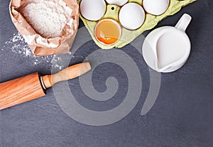 Baking ingredients and tools on the black stone background