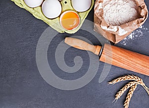 Baking ingredients and tools on the black stone background