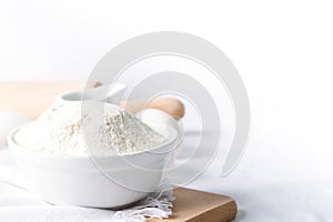 Baking ingredients. White background. Ingredients and tools to make a cake. Flour, milk, eggs, rolling pin, wooden spoons, jar.