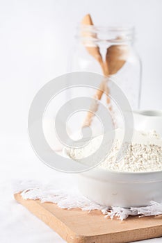 Baking ingredients. White background. Ingredients and tools to make a cake. Flour, milk, eggs, rolling pin, wooden spoons, jar.