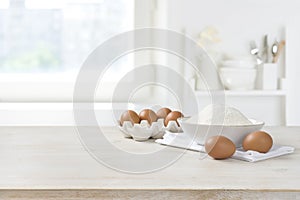 Baking ingredients on wooden table over defocused kitchen window background