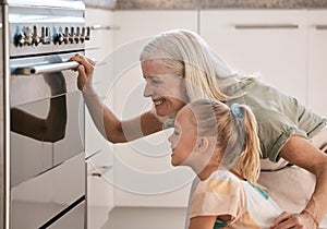 Baking, kitchen and grandmother with a child by the oven watching the cake, cookies or pie bake. Happy, smile and senior