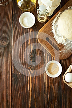 Baking in rural kitchen. Dough and recipe ingredients on vintage brown wooden table. Top view. Rustic background