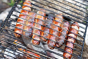 Baking Sausage BBQ hot dog kebab roasted on campfire in nature closeup