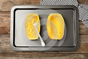 Baking sheet with cooked spaghetti squash and fork on table