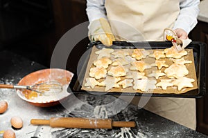 On a baking sheet with parchment, hot freshly baked puff sweet cookies against the background of a black kitchen table with spille