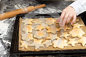 On a baking sheet with parchment, hot freshly baked puff sweet cookies against the background of a black kitchen table with spille