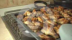 A baking sheet is placed on the stove with spicy chicken wings freshly baked in the oven